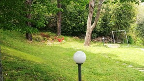 A grassy area with a swing set and a spherical object on a pole. - Villa bifamiliare panoramica in collina con grande giardino (Schignano)