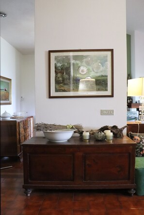 Una habitación con un armario de madera, un cuadro enmarco y un cuenco con flores secas.