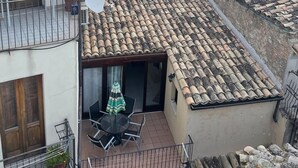 A courtyard with a table and chairs, a red-tiled roof, and a view of the surrounding buildings. - Stay in the tranquility of Badolato's ancient, atmospheric streets (Badolato)
