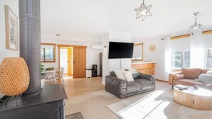 Een moderne woonkamer met een open haard, een flatscreen televisie en een eethoek met een tafel en stoelen.