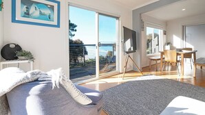 A modern living room with a large sliding glass door leading to a balcony with a view of the sea.