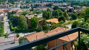 Une vue panoramique d’une ville, avec une chaîne de montagnes en arrière-plan, comprenant un mélange de bâtiments résidentiels et commerciaux, un ciel dégagé et une route principale traversant le centre-ville.