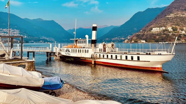 Un traversier accosta à un quai, avec une chaîne de montagnes en toile de fond.
