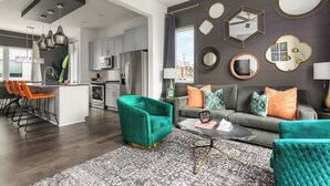 Una sala de estar moderna con un sofá gris, sillones turquesa y una mesa de centro.