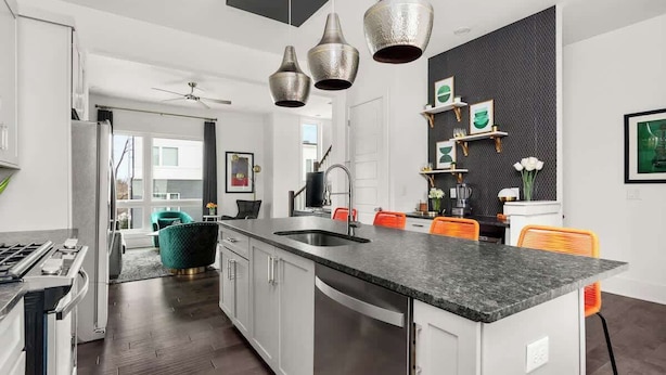 Una cocina moderna con una isla central, electrodomésticos de acero inoxidable y un salpicadero negro.