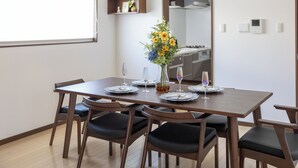 A dining area with a wooden table set for four, surrounded by chairs. - OYADO - Self Check-In Only (Osaka)