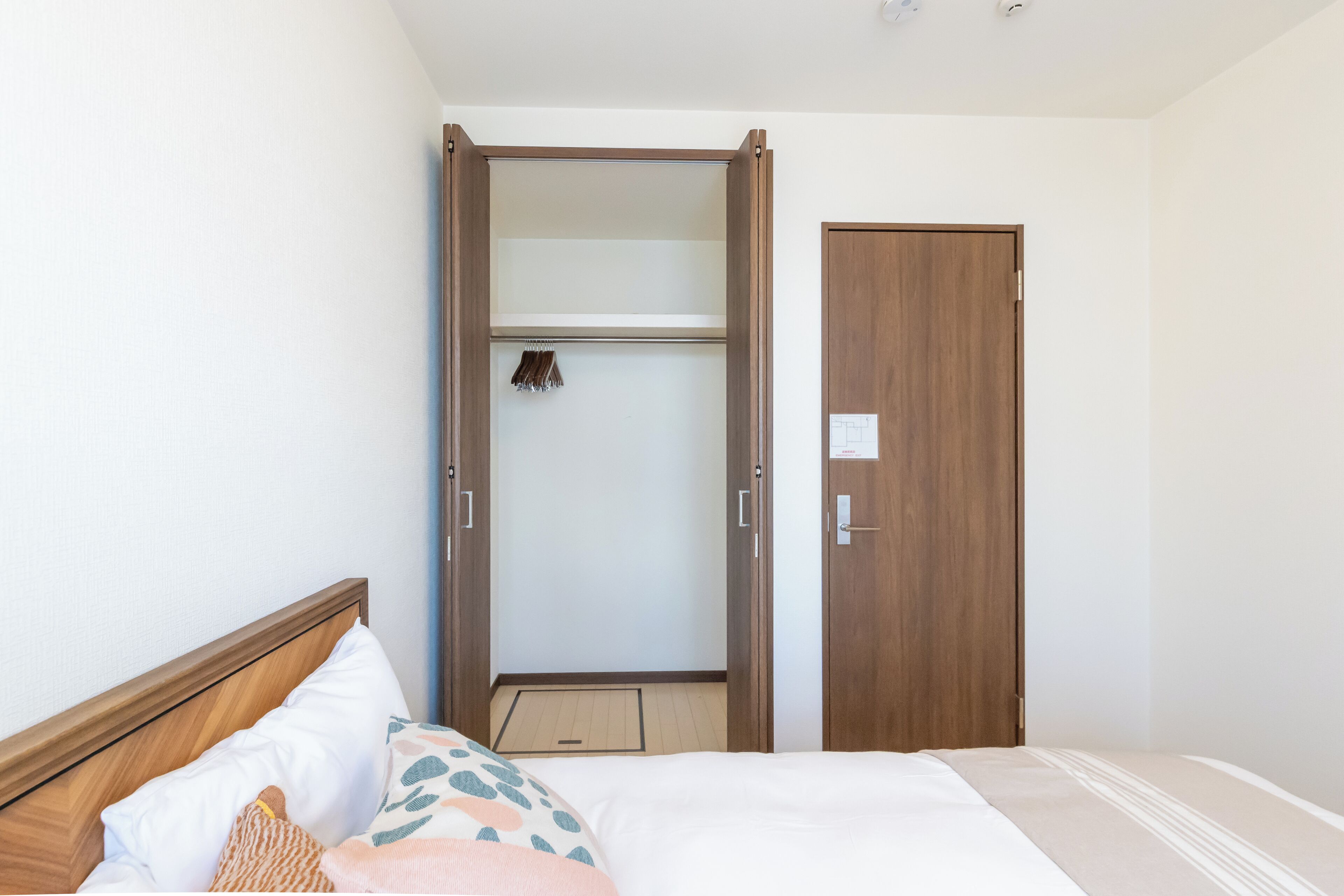 A bedroom with a bed, a wooden wardrobe, and a door.