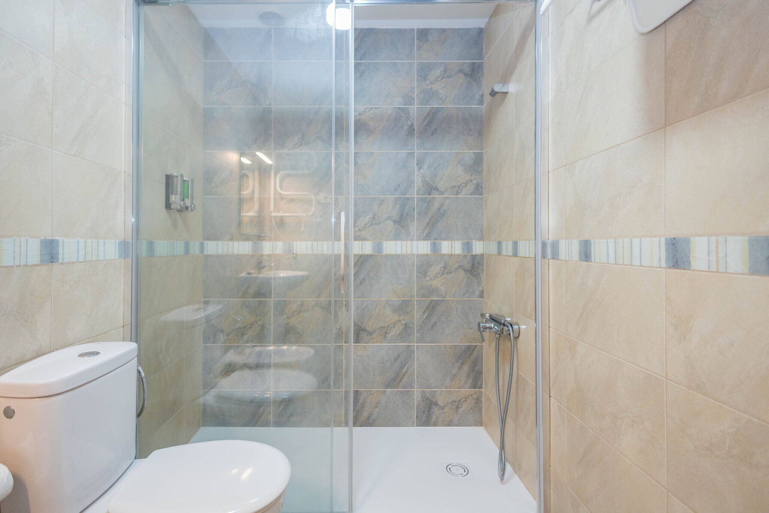 Un bagno moderno con doccia vetrata, un water e un lavandino.