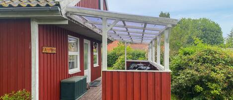 Een rood gebouw met een overdekte veranda en een kleine, groene schuur.