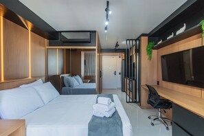 Una habitación de hotel moderna con una cama grande, un escritorio, un televisor y un vestidor.