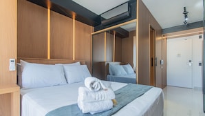 A hotel room with a large bed, a bedside control panel, a mirror, and a door with a keycard lock.