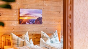 A wooden room with a bed, pillows, and a painting of a mountain landscape. - Apartment 'Höllental' with Mountain View, Balcony, and Wi-Fi (Grainau)