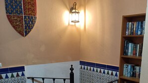 Un escalier orné de rampes noires, un luminaire fixé au mur et une bibliothèque remplie de livres.