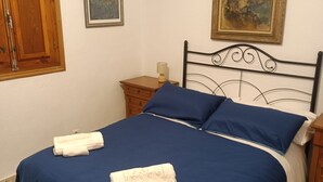 Un lit bien fait, avec une literie bleue et deux serviettes blanches posées dessus.