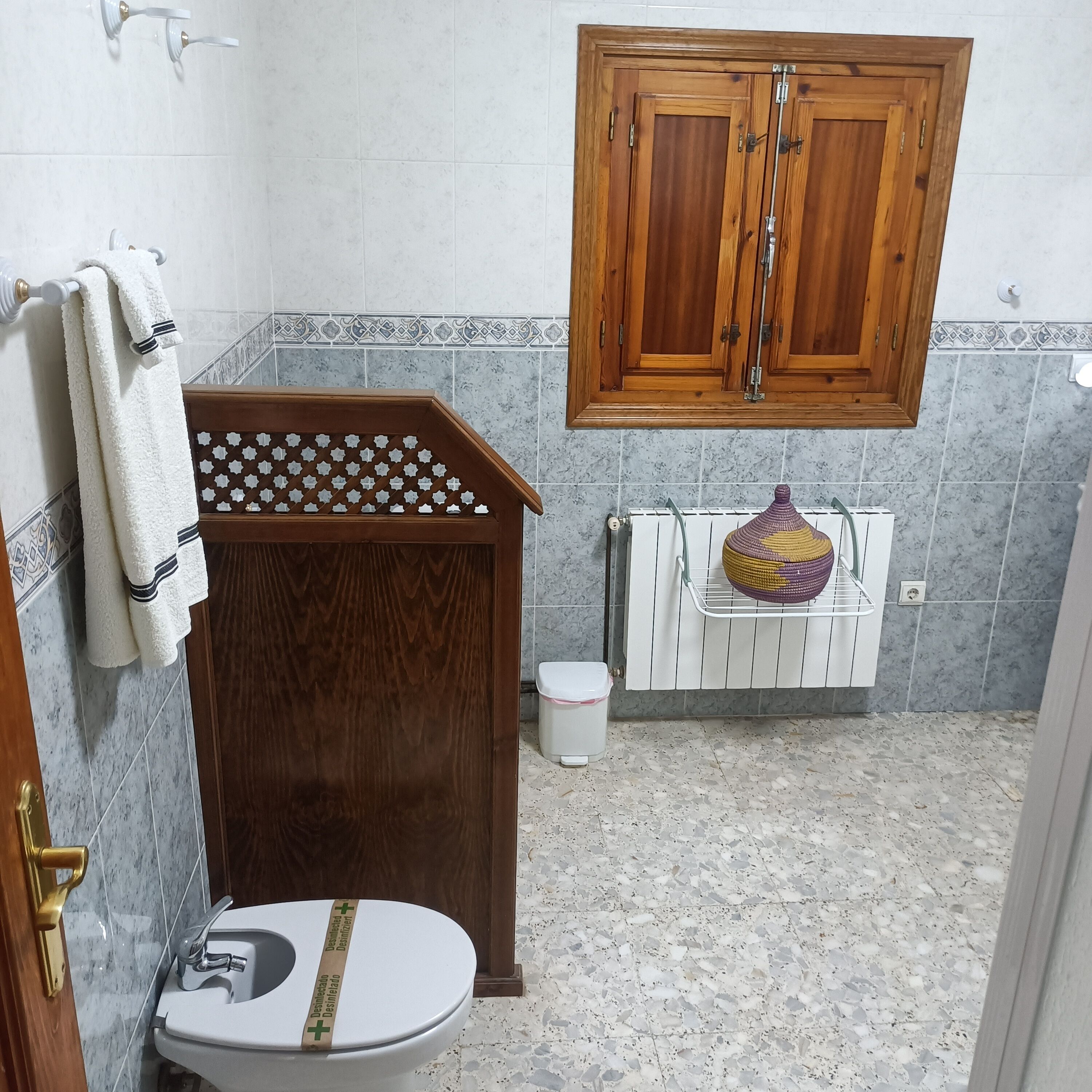 Un baño con tocador de madera, inodoro, lavamanos y un mueble sobre el inodoro.