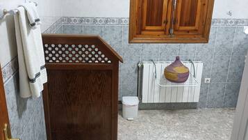 Un baño con tocador de madera, inodoro, lavamanos y un mueble sobre el inodoro.