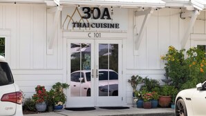 A Thai cuisine restaurant with a white facade, double doors, and potted plants in front. - IndiGo Blue- Golf Cart! Pool & Fitness Center (Santa Rosa Beach)