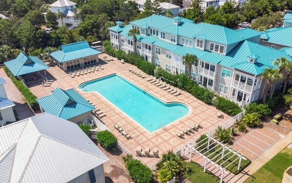 A resort with a large pool, multiple buildings with blue roofs, and outdoor seating areas.