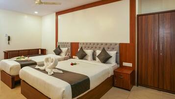 A hotel room with two beds, a wardrobe, a bedside table, and a ceiling fan.