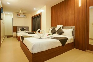 A hotel room with two beds, wooden paneling, a ceiling fan, and a window with curtains.