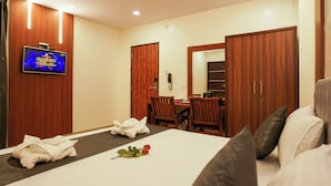A hotel room with a bed, a TV, a desk, and a wardrobe. - Royal Plaza City (Kozhikode)
