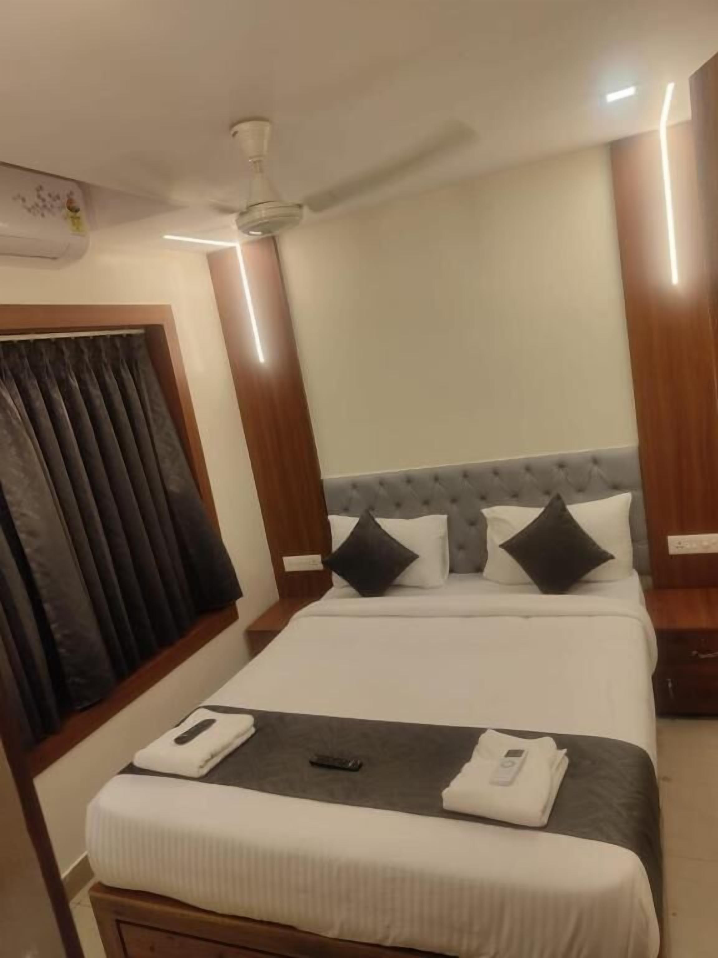 Una habitación de hotel con cama, ventilador de techo y ventana con cortinas.
