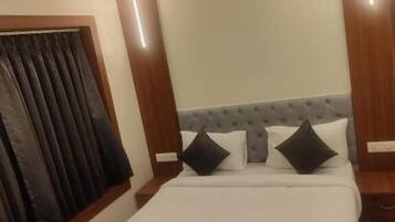Una habitación de hotel con cama, ventilador de techo y ventana con cortinas.
