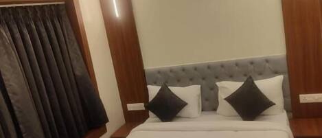 A hotel room with a bed, a ceiling fan, and a window with curtains.