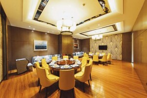 A dining area with a round table, yellow chairs, and a chandelier.