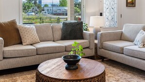 A living room with two sofas, a round coffee table, and a view of a cityscape through large windows.