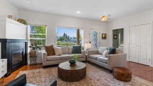 A modern living room with a fireplace, two sofas, a coffee table, and a view of the outdoors.