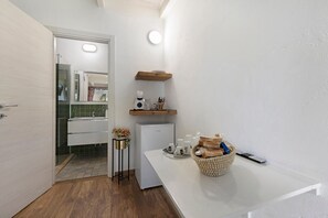 A compact kitchen with a refrigerator, a sink, and a small table with a basket.