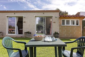 A patio with a table and chairs, a basket of bread, and a small building with a nameplate.