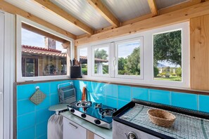 A kitchen with a gas stove, a sink, and a window with a view of the outdoors.