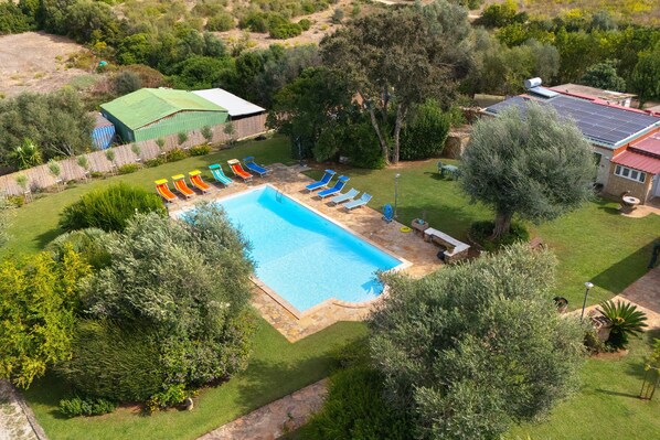 A swimming pool with multiple sun loungers and a small garden area.
