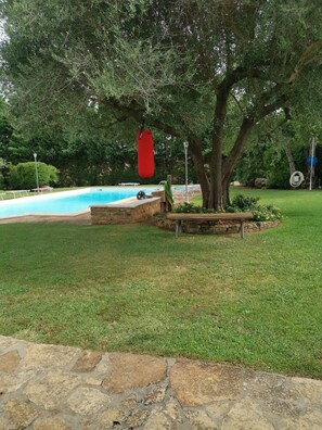 Ein Swimmingpool, ein roter Sandsack und ein Baum im Hinterhof.