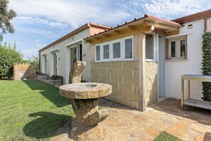 A house with a stone patio, a stone well, and a small garden.