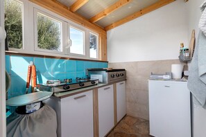 A compact kitchen with a gas stove, a small refrigerator, and a window with a view of trees. - Apartment 'Mirto' with shared pool, Wi-Fi and air conditioning (Alghero)
