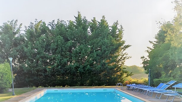 A rectangular swimming pool with a tiled edge, surrounded by a stone deck, and backed by dense green foliage. - Apartment 'Rosmarino' with Shared Pool, Wi-Fi and Air Conditioning (Alghero)
