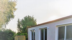 A modern house with a well-maintained lawn, large windows, and potted plants. - Apartment 'Rosmarino' with Shared Pool, Wi-Fi and Air Conditioning (Alghero)
