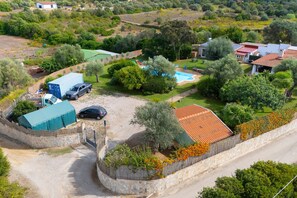 A residential area with a swimming pool, parked vehicles, and a stone wall. - Apartment 'Rosmarino' with shared pool, Wi-Fi and air conditioning (Alghero)