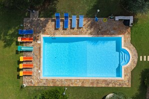 An aerial view of a swimming pool with a stone border, surrounded by grass and a stone wall. - Apartment 'Rosmarino' with shared pool, Wi-Fi and air conditioning (Alghero)