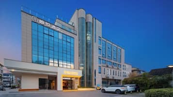A modern hotel with a prominent entrance, large windows, and a parking area.