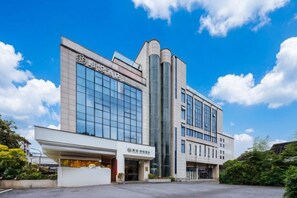 Un edificio moderno con una amplia fachada de vidrio, una estructura vertical destacada y un techo plano.