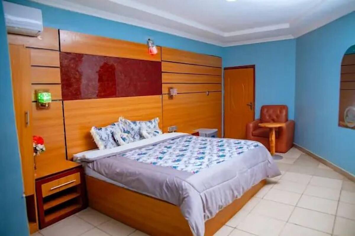 Ein Schlafzimmer mit einem hölzernen Bett, einem Nachttisch, einem Stuhl und einem kleinen Tisch.
