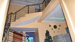 A multi-level interior with a staircase, a Christmas tree, and a modern ceiling design. - The Kings Hotel and Suites  (Ibadan)