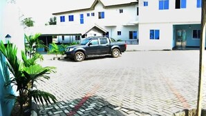 A building with a paved courtyard and a parked vehicle. - The Kings Hotel and Suites  (Ibadan)