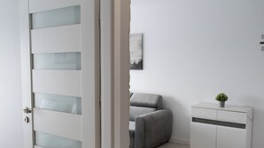 A room with a white wardrobe, a grey sofa, and a small plant on top. - RentPlanet - Apartament przy Lotnisku (Poznań)
