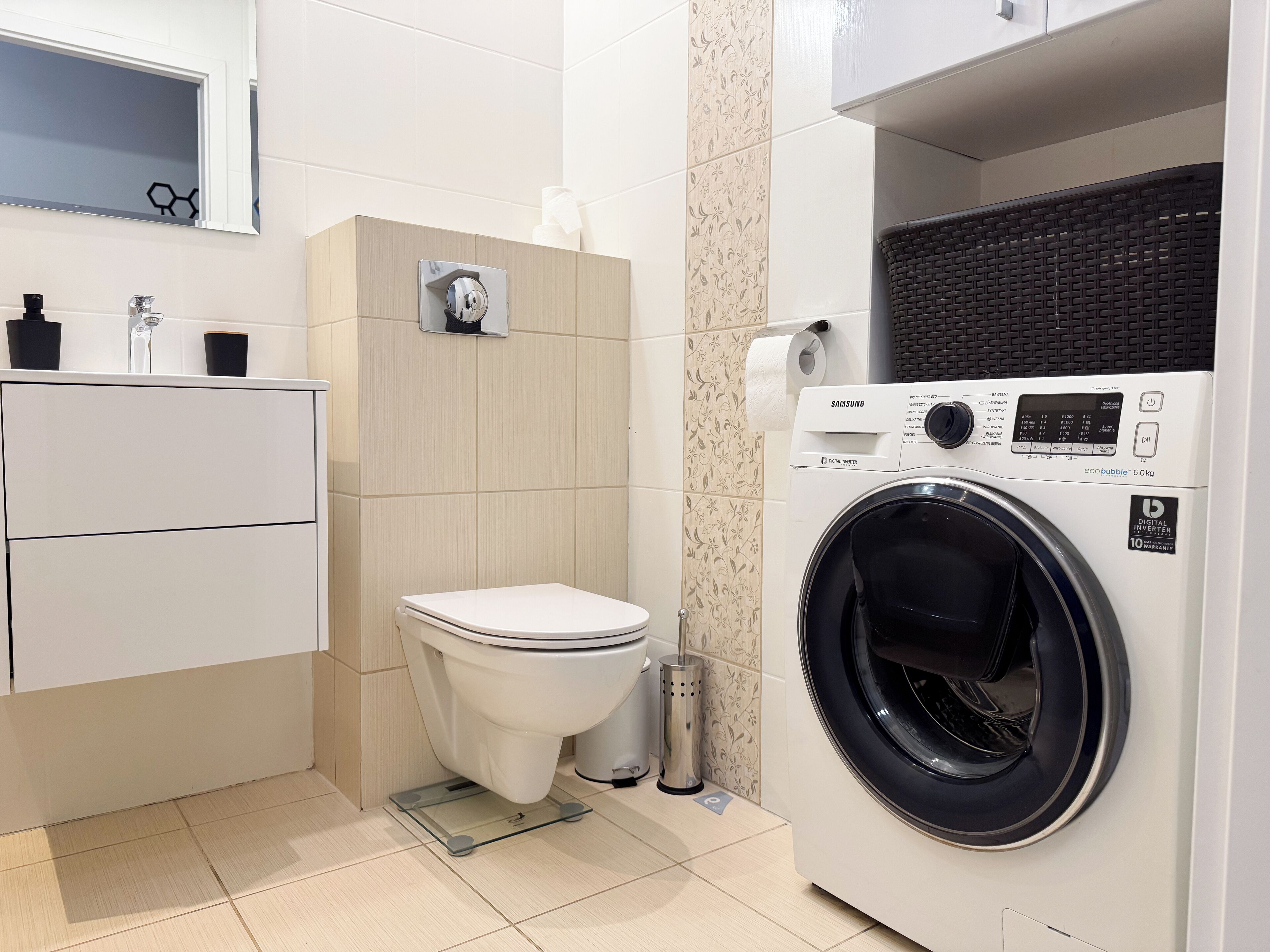 Une salle de bain moderne équipée de toilettes, d’un lave-linge et d’un lavabo.