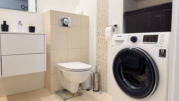 A modern bathroom with a toilet, a washing machine, and a sink.
